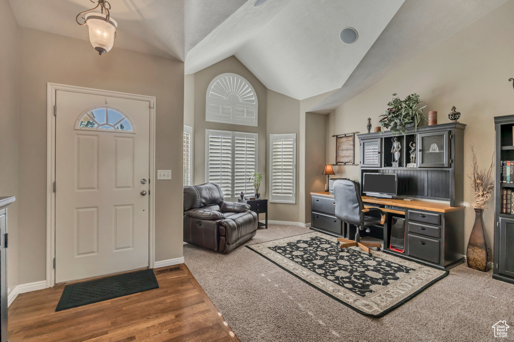 Entrance foyer featuring baseboards, wood finished floors, and high vaulted ceiling