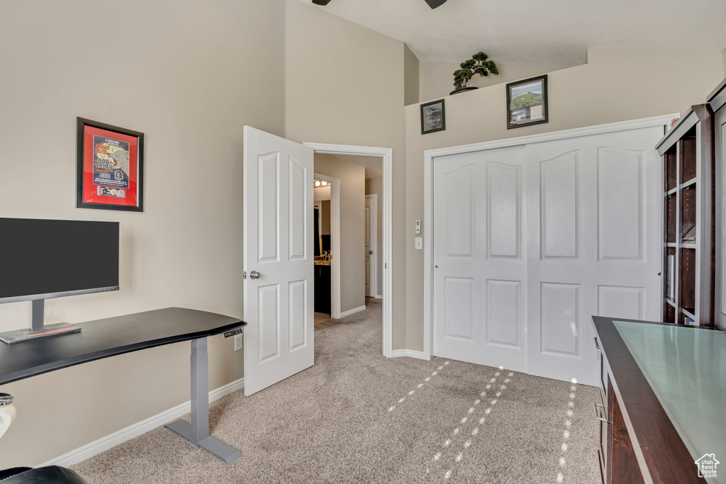 Unfurnished office with light carpet, baseboards, and high vaulted ceiling