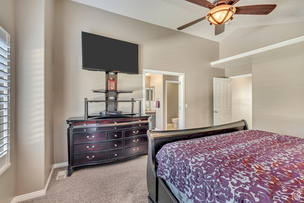 Carpeted bedroom featuring baseboards, connected bathroom, vaulted ceiling, and ceiling fan