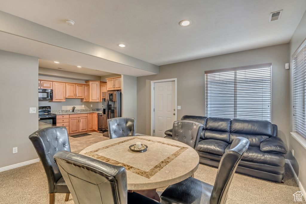 Dining area featuring light colored carpet, baseboards, recessed lighting, and plenty of natural light