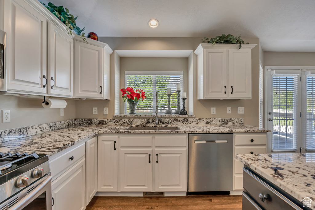 Kitchen with appliances with stainless steel finishes, white cabinets, a sink, plenty of natural light, and recessed lighting