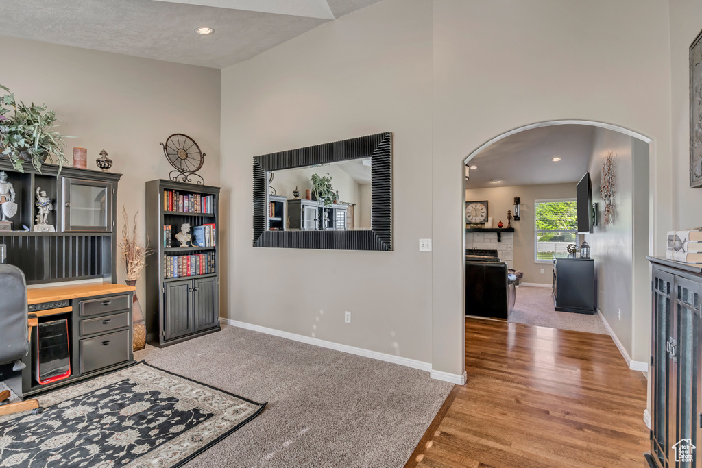 Office with arched walkways, baseboards, light wood-style flooring, recessed lighting, and light carpet