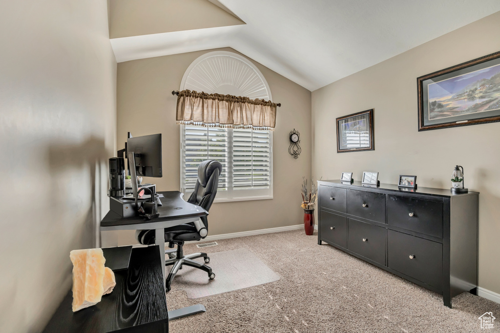 Carpeted office with lofted ceiling and baseboards
