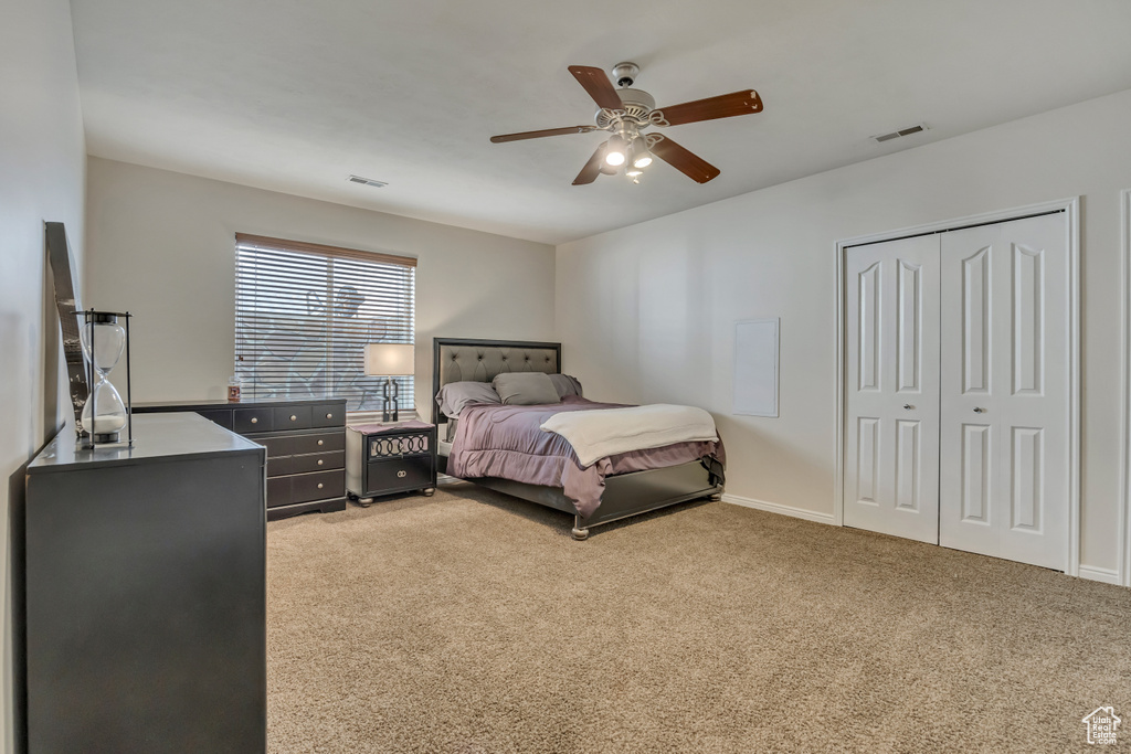 Bedroom featuring light colored carpet, a ceiling fan, a closet, and baseboards