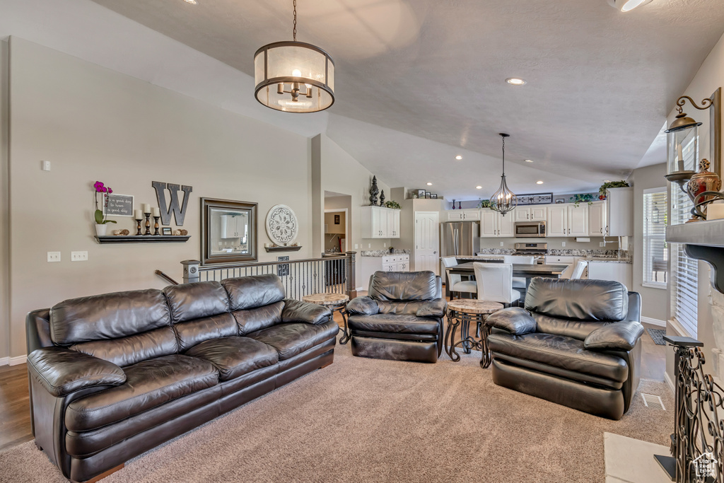 Carpeted living room with a chandelier, lofted ceiling, baseboards, and recessed lighting