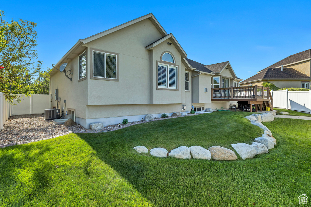 Rear view of property featuring a deck, stucco siding, and cooling unit