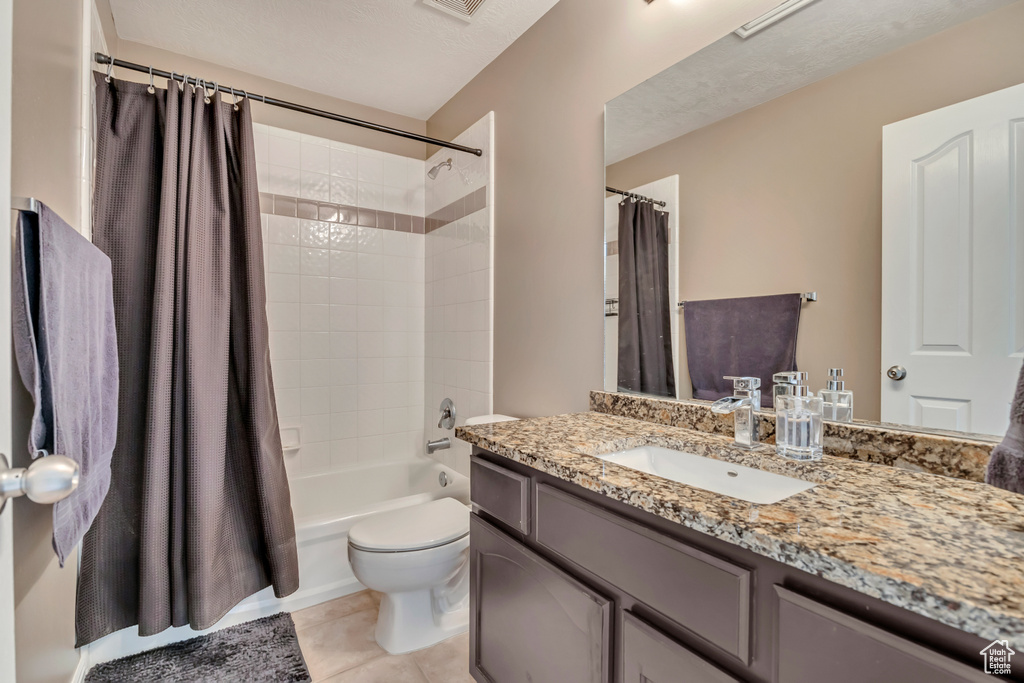 Bathroom featuring vanity, toilet, shower / bath combo, and tile patterned flooring