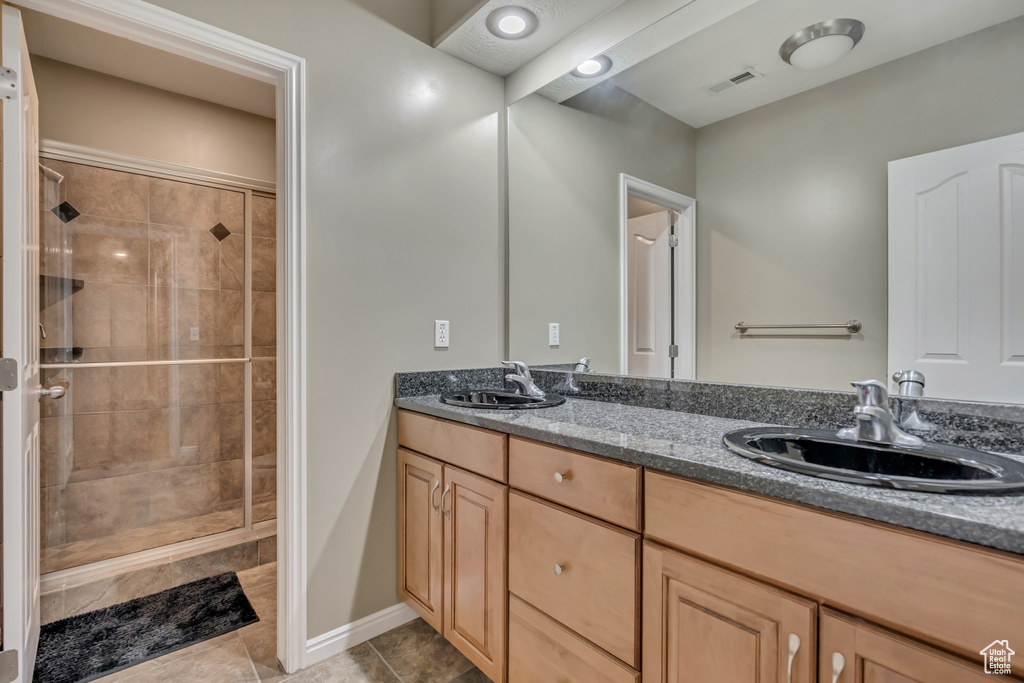 Full bathroom featuring double vanity, a stall shower, and tile patterned flooring