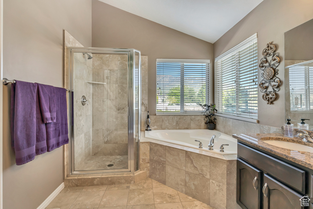 Full bathroom featuring healthy amount of natural light, vaulted ceiling, a garden tub, and a shower stall