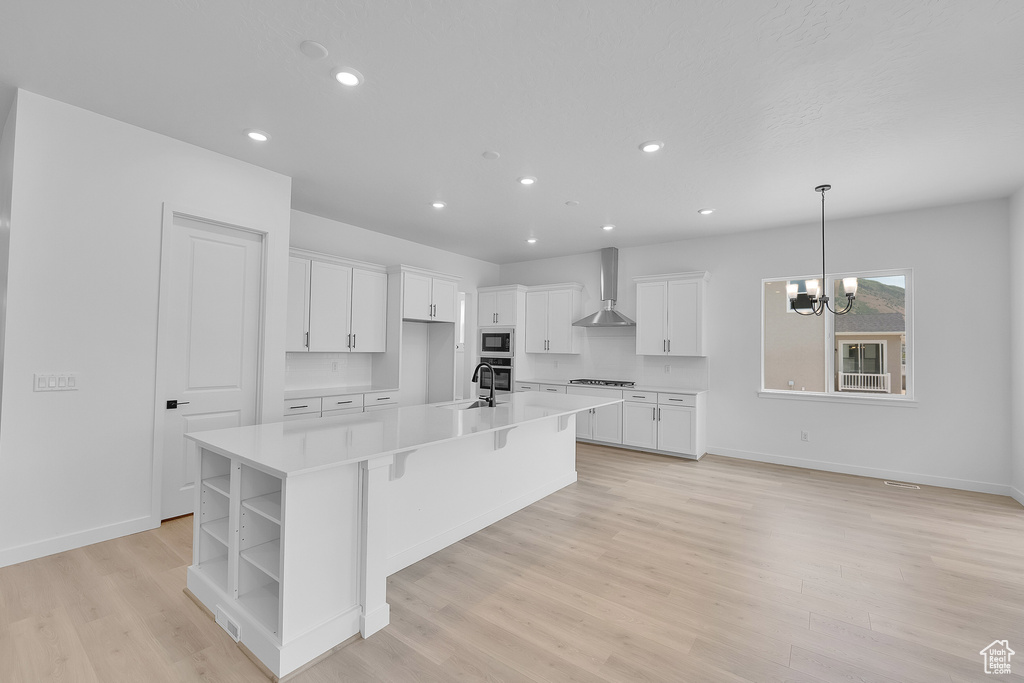 Kitchen featuring wall chimney exhaust hood, a sink, built in microwave, open shelves, and white cabinetry