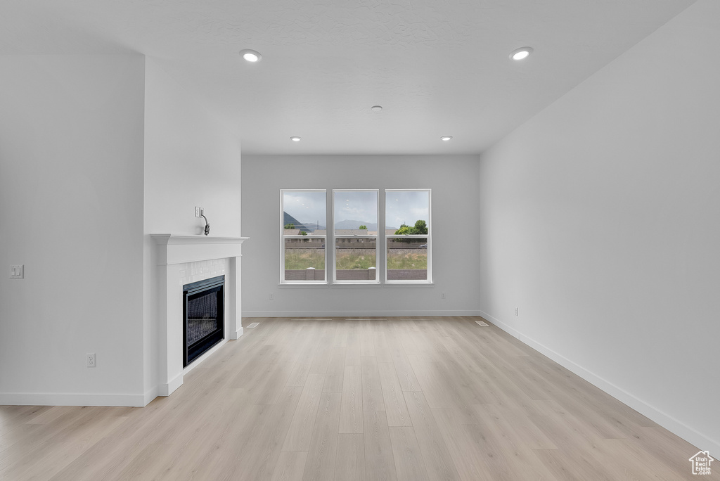 Unfurnished living room featuring a fireplace, light wood-style flooring, baseboards, and recessed lighting