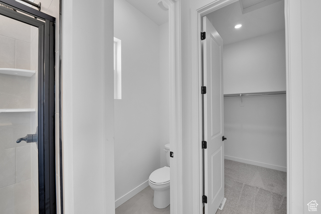 Bathroom featuring toilet, a shower stall, a walk in closet, baseboards, and recessed lighting