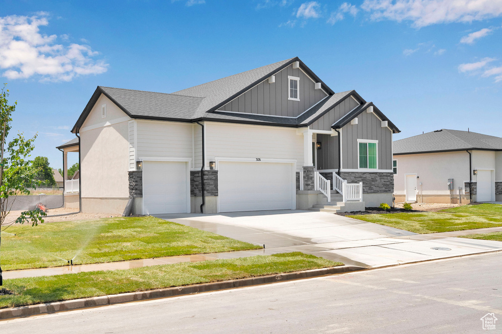 Craftsman inspired home featuring board and batten siding, driveway, stone siding, and a garage