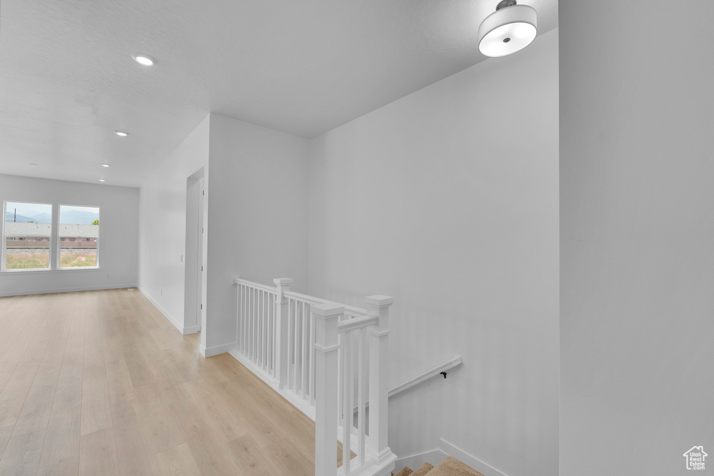 Hallway featuring an upstairs landing, wood finished floors, recessed lighting, and baseboards