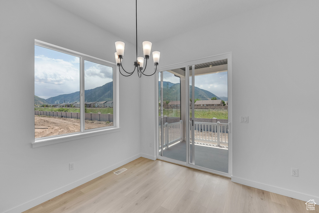 Unfurnished dining area featuring a mountain view, a chandelier, wood finished floors, and plenty of natural light