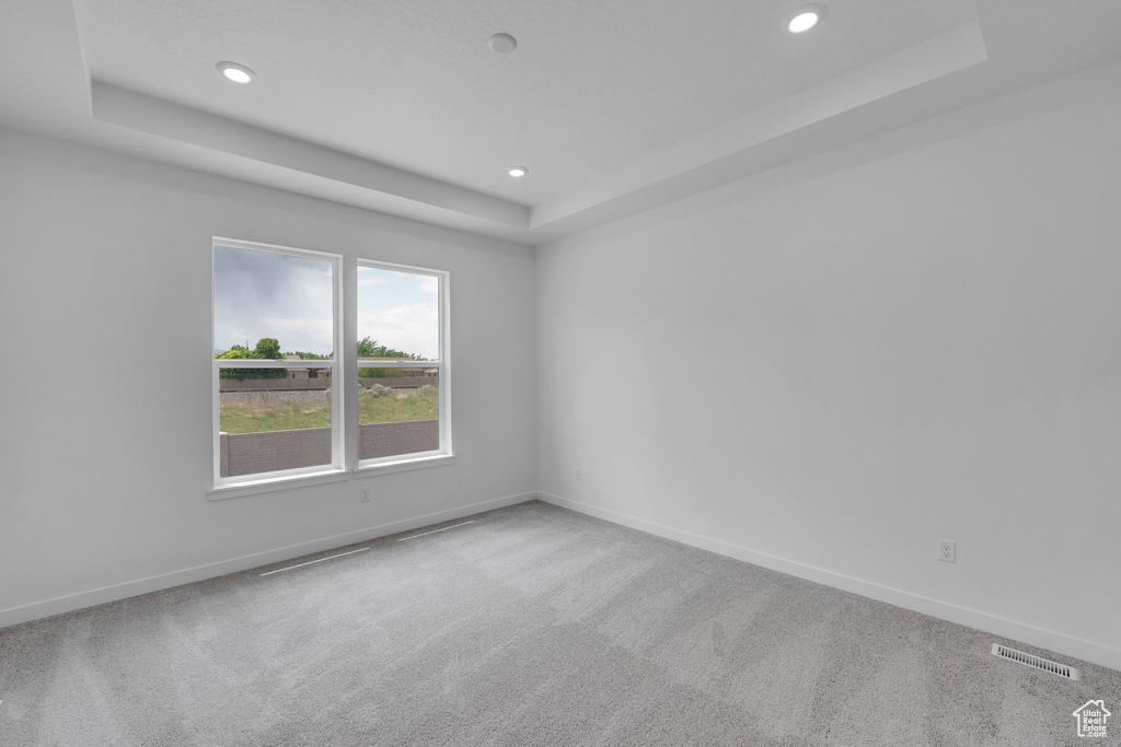 Carpeted spare room with a raised ceiling, baseboards, and recessed lighting