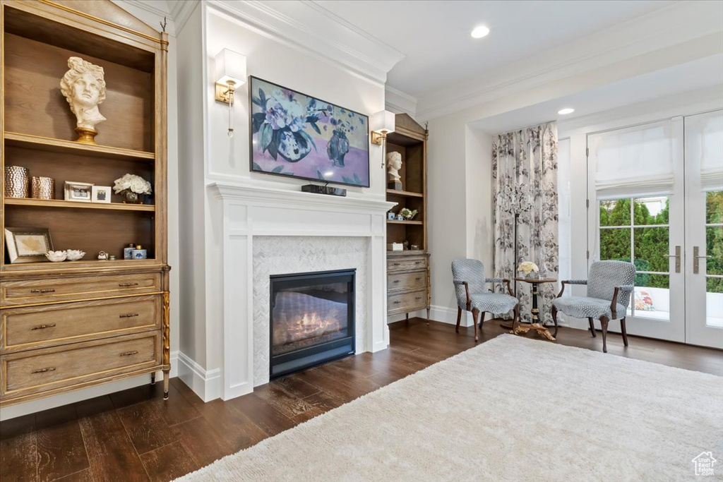 Living area featuring a glass covered fireplace, ornamental molding, dark wood finished floors, baseboards, and recessed lighting