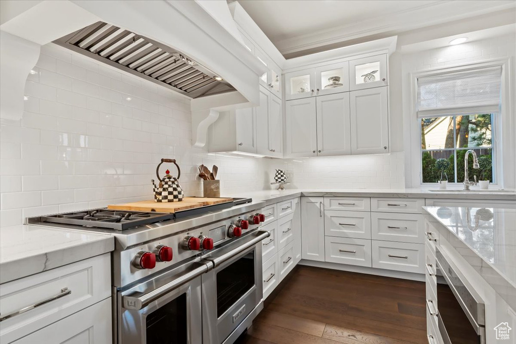 Kitchen with double oven range, a sink, custom exhaust hood, backsplash, and ornamental molding