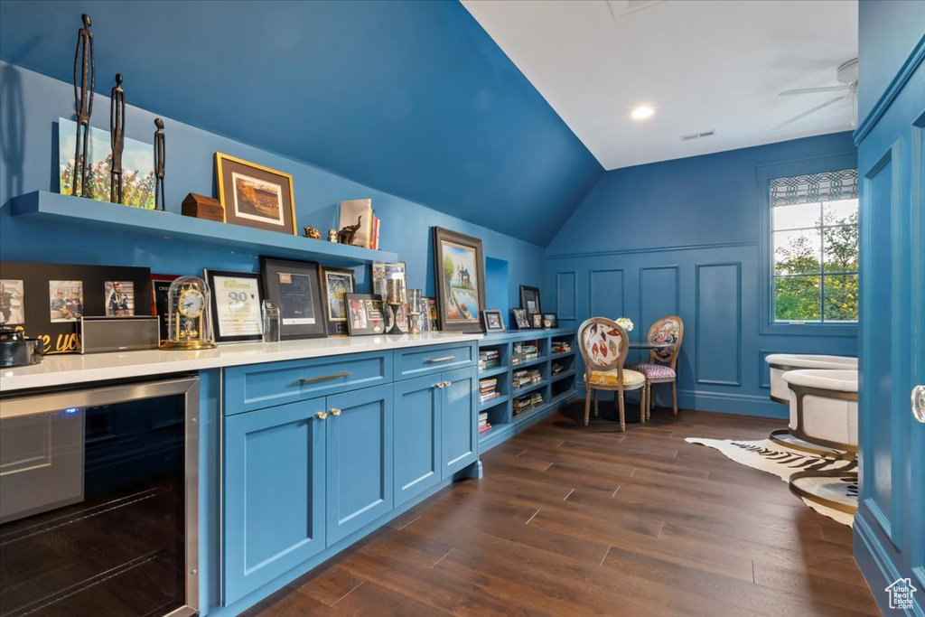 Indoor dry bar featuring beverage cooler, lofted ceiling, and dark wood finished floors