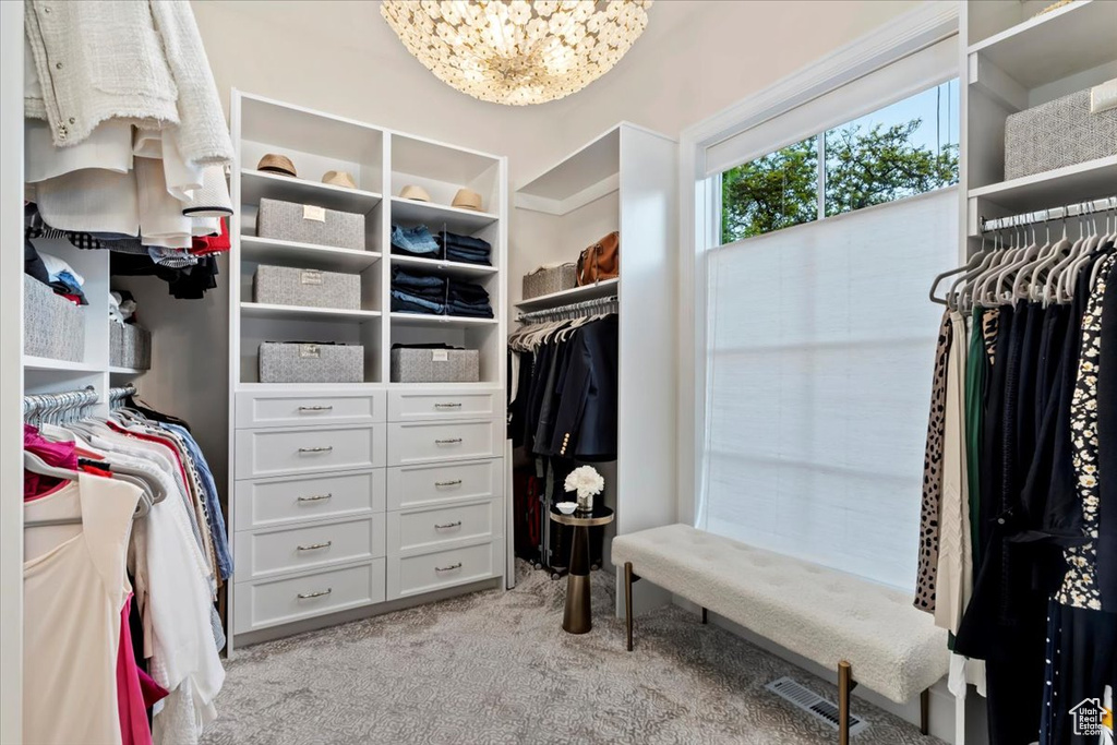 Walk in closet featuring light colored carpet and a chandelier