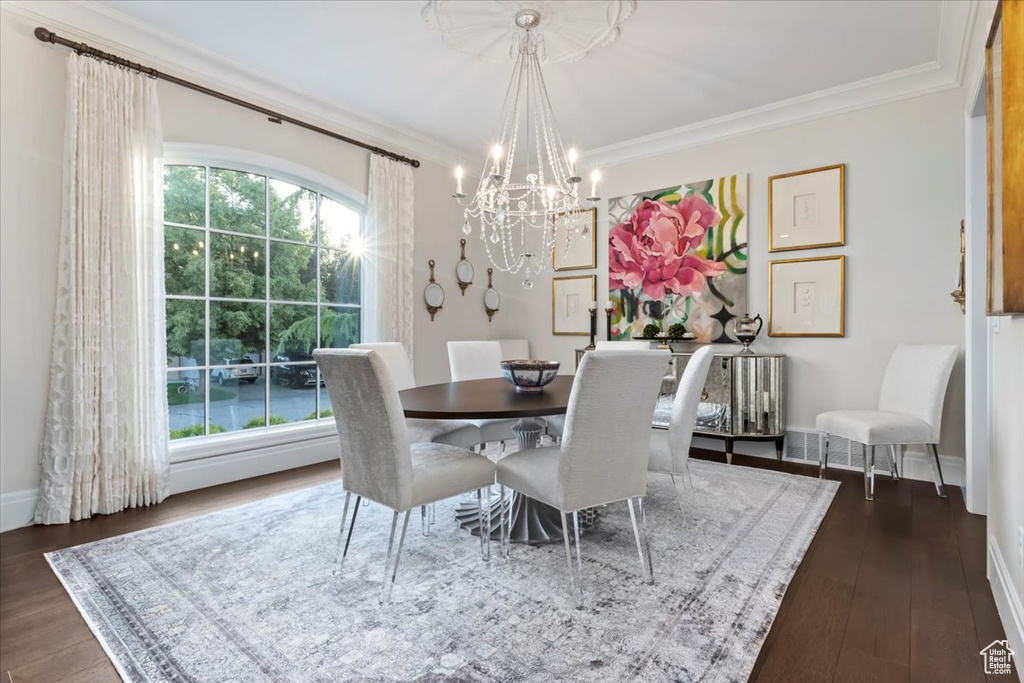 Dining area featuring a chandelier, dark wood finished floors, crown molding, and baseboards