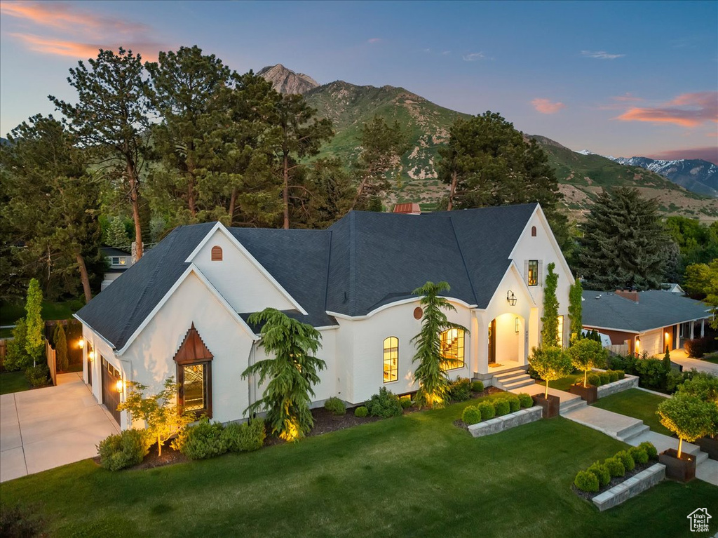 View of front of home with driveway, stucco siding, a mountain view, an attached garage, and a front yard