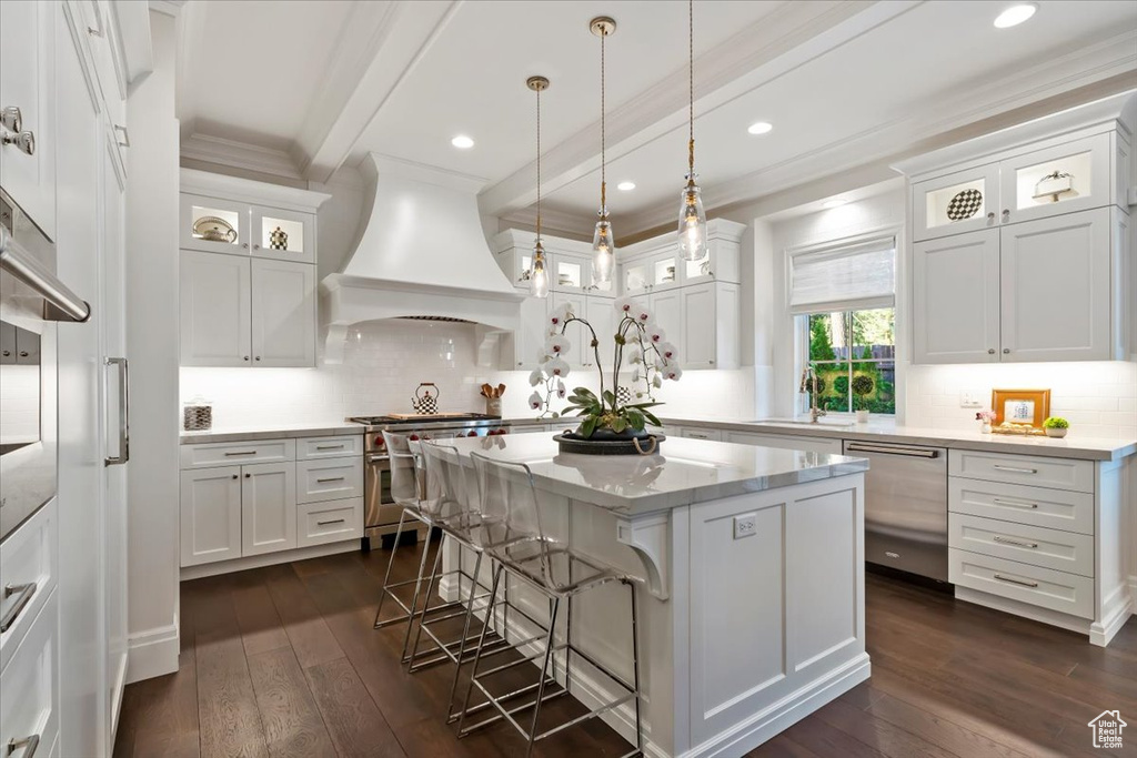 Kitchen with appliances with stainless steel finishes, custom range hood, ornamental molding, white cabinetry, and recessed lighting