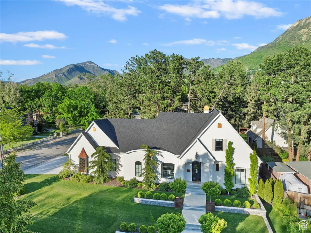 French country style house with a mountain view, a front yard, and stucco siding