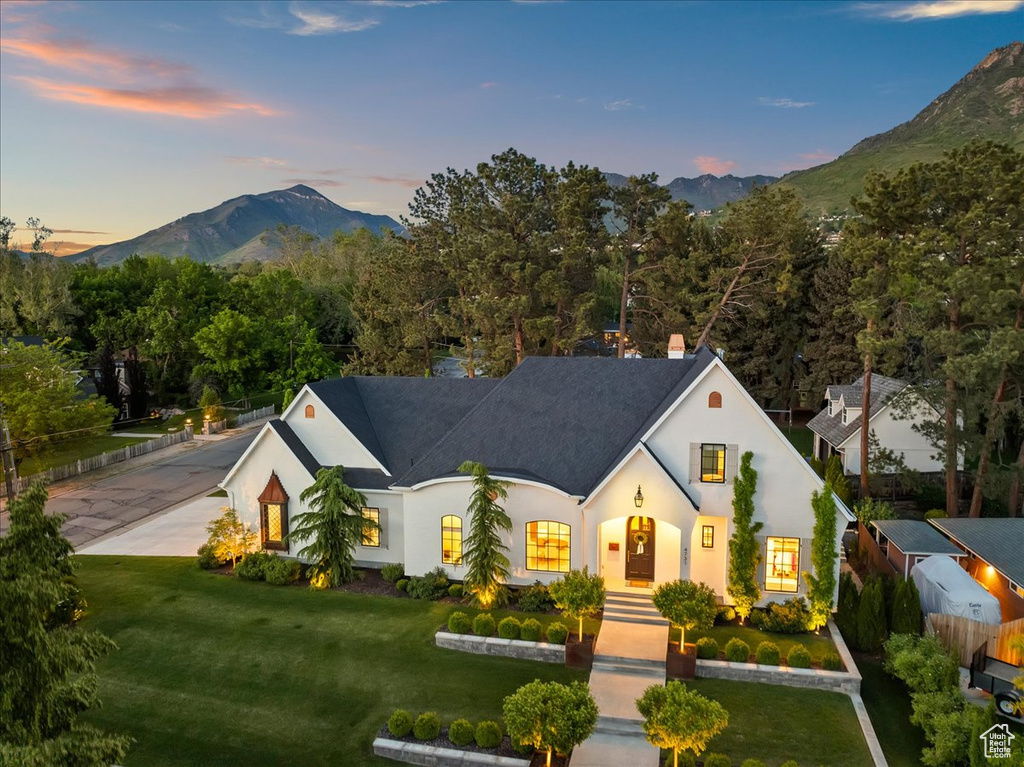 French provincial home featuring a mountain view, a front yard, stucco siding, and a chimney