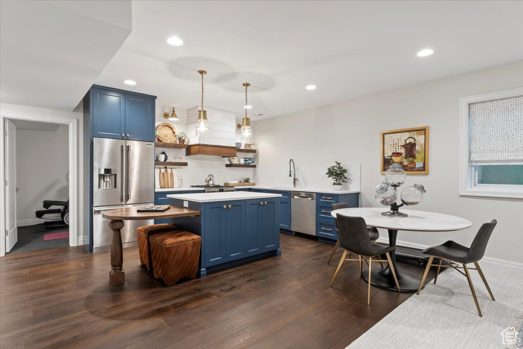 Kitchen with stainless steel appliances, blue cabinets, open shelves, light countertops, and recessed lighting