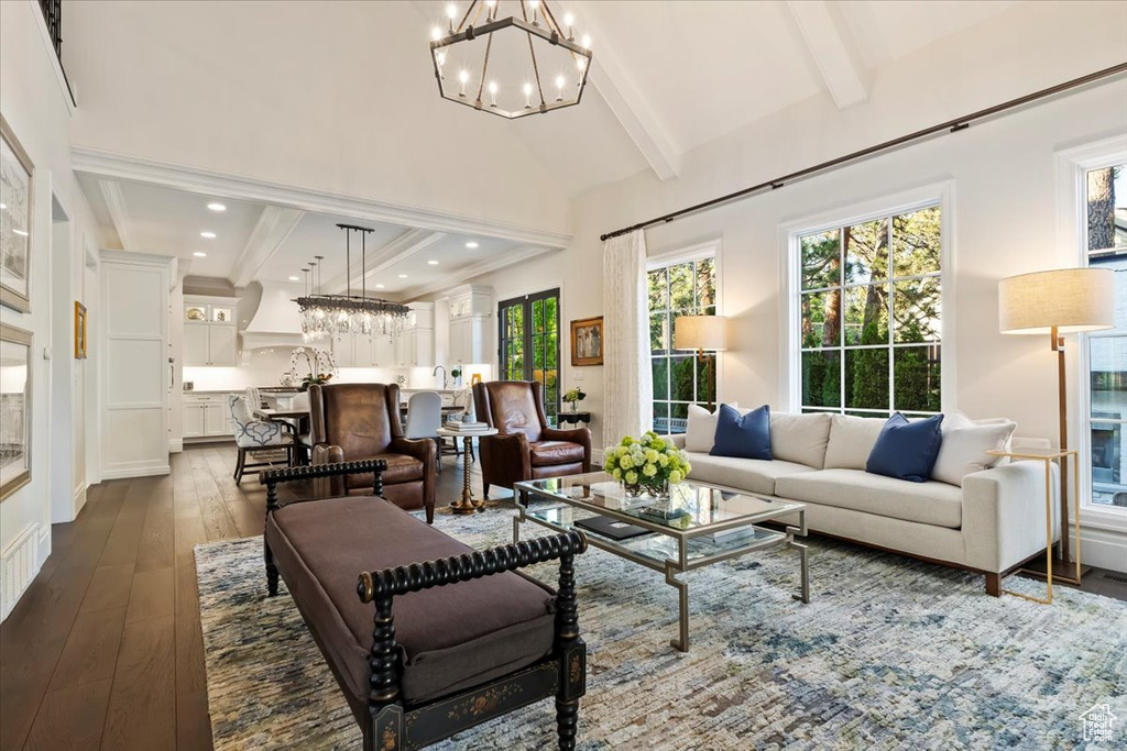 Living area with a chandelier, dark wood finished floors, healthy amount of natural light, beam ceiling, and recessed lighting
