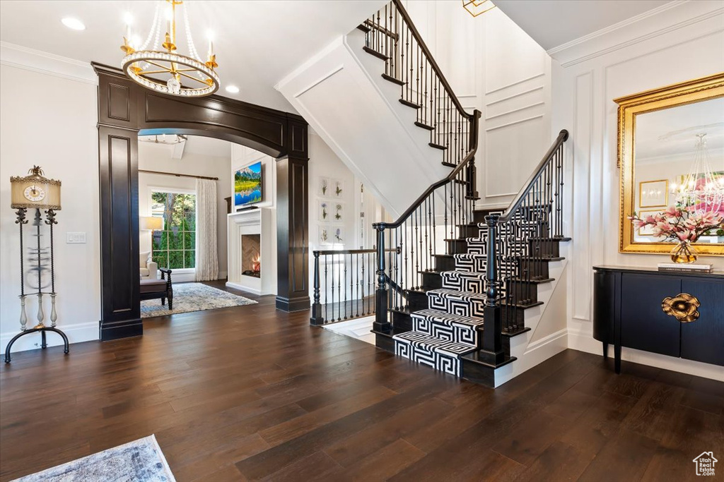 Foyer featuring a chandelier, wood finished floors, stairway, baseboards, and crown molding