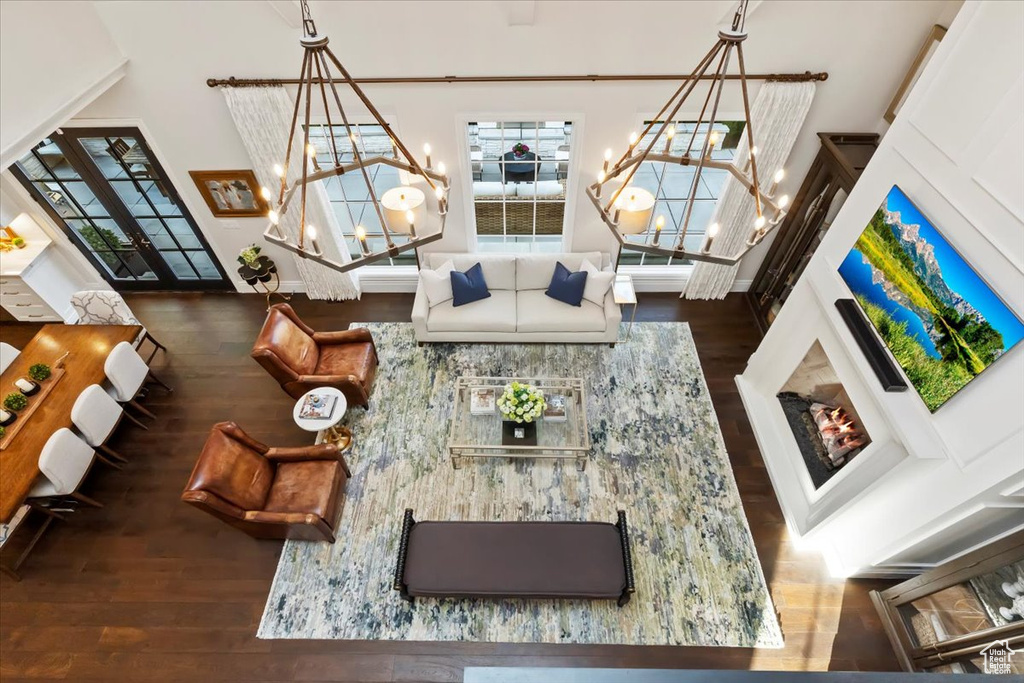 Living area with a chandelier, wood finished floors, and a towering ceiling