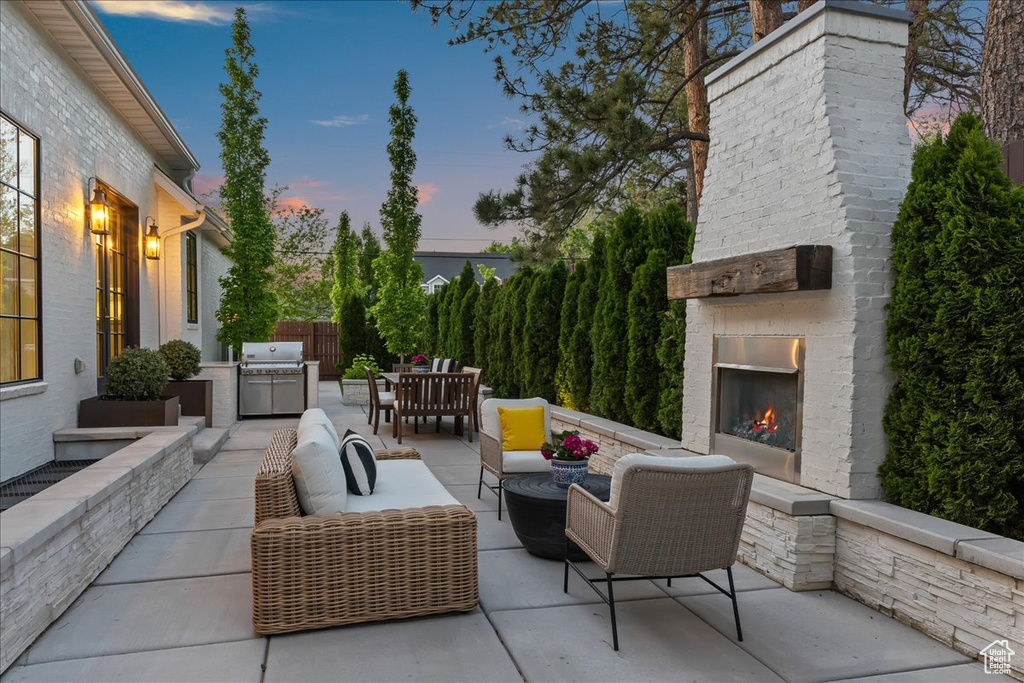 Patio terrace at dusk with a patio area and an outdoor living space with a fireplace