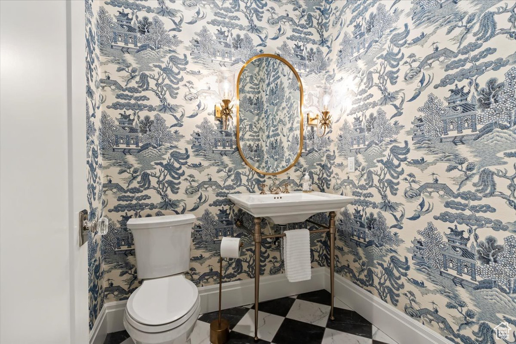 Half bath featuring baseboards, wallpapered walls, and toilet