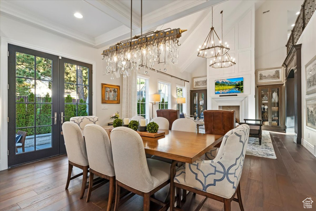 Dining area featuring beamed ceiling, a chandelier, french doors, dark wood-type flooring, and a towering ceiling