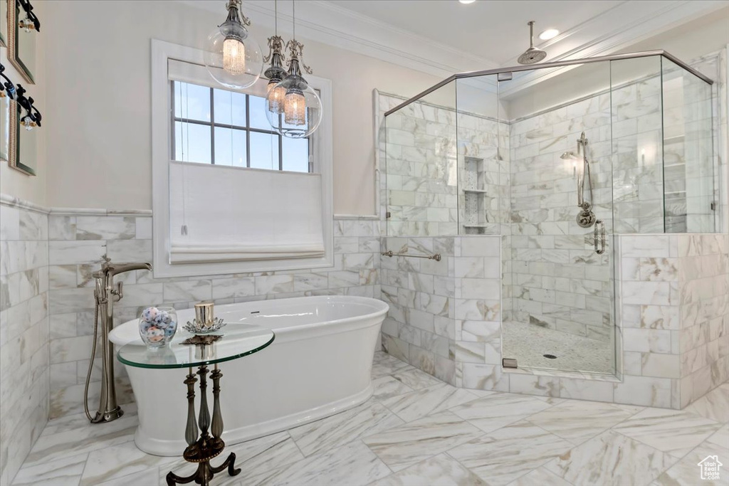 Bathroom with a stall shower, crown molding, marble finish flooring, a freestanding bath, and tile walls