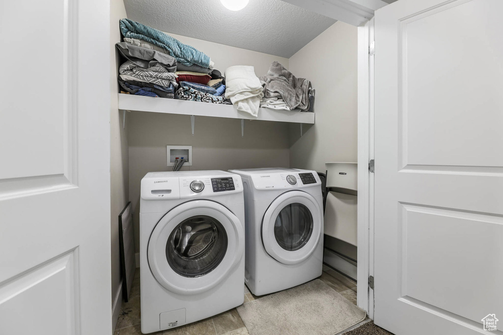 Laundry room featuring washer and clothes dryer and a textured ceiling