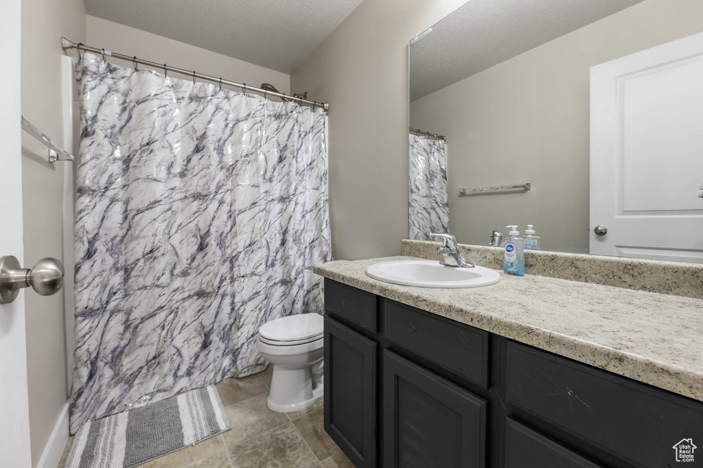 Bathroom featuring vanity, toilet, curtained shower, and tile patterned floors