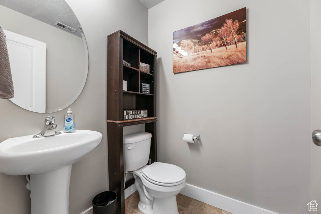 Bathroom featuring baseboards, toilet, tile patterned flooring, and a sink