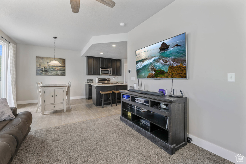 Living area with ceiling fan, baseboards, light wood-style flooring, and recessed lighting