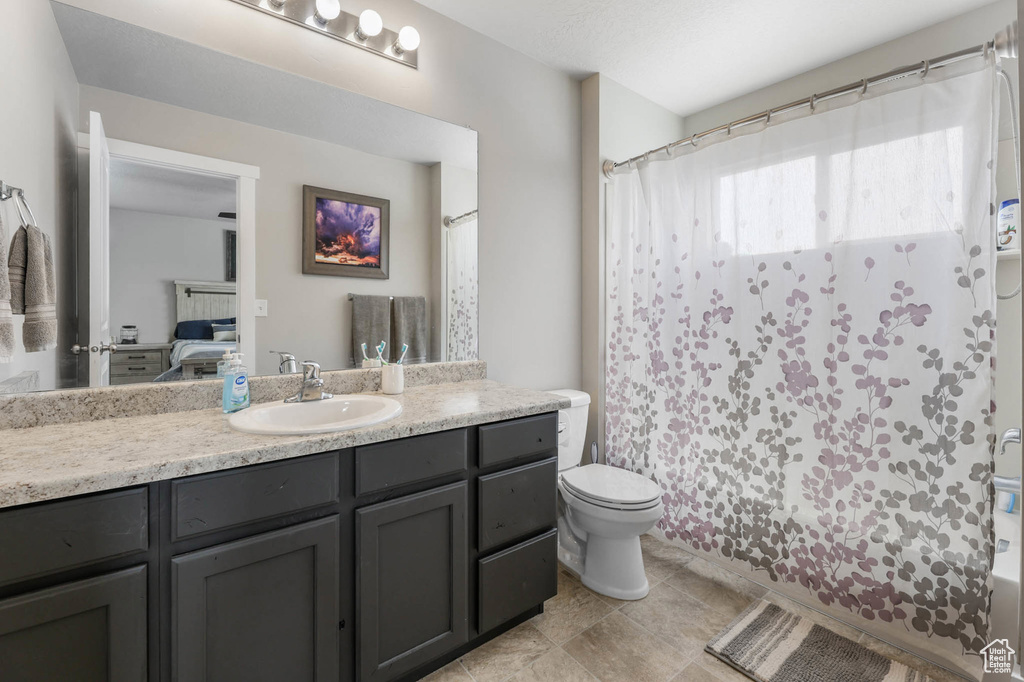 Ensuite bathroom featuring vanity, toilet, shower / tub combo with curtain, and tile patterned flooring