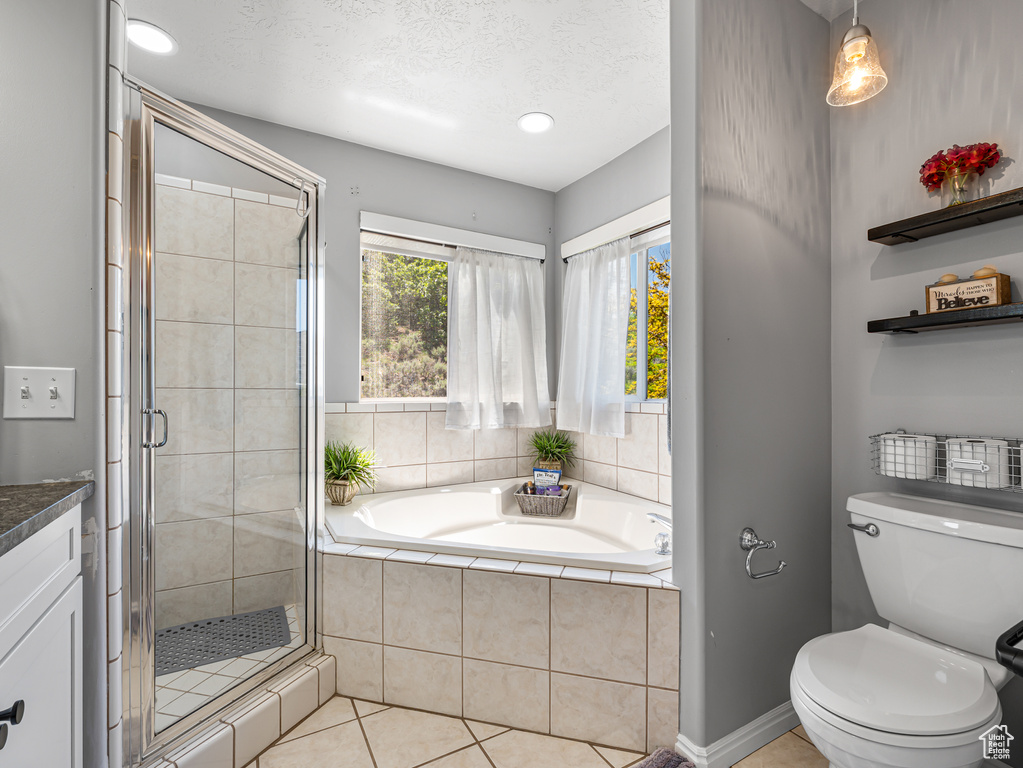Full bath with a bath, a shower stall, tile patterned flooring, toilet, and vanity