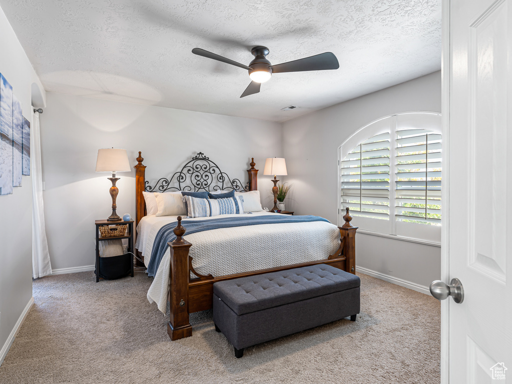 Carpeted bedroom with a textured ceiling, baseboards, and ceiling fan