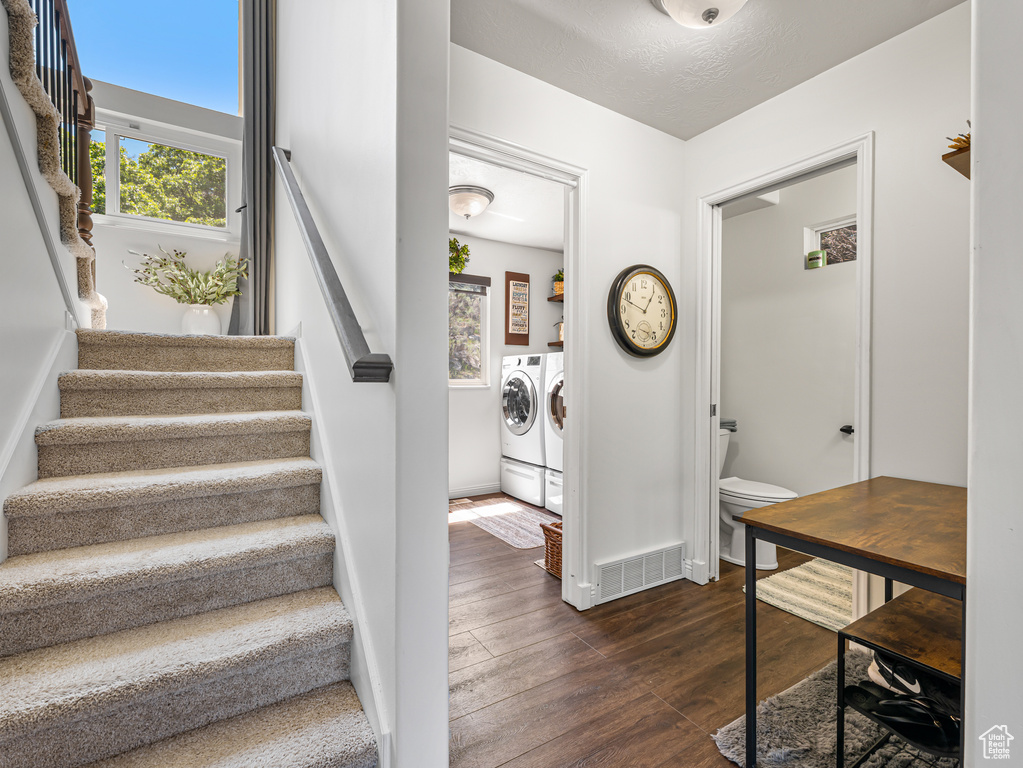 Staircase with washer and dryer, wood-type flooring, and baseboards