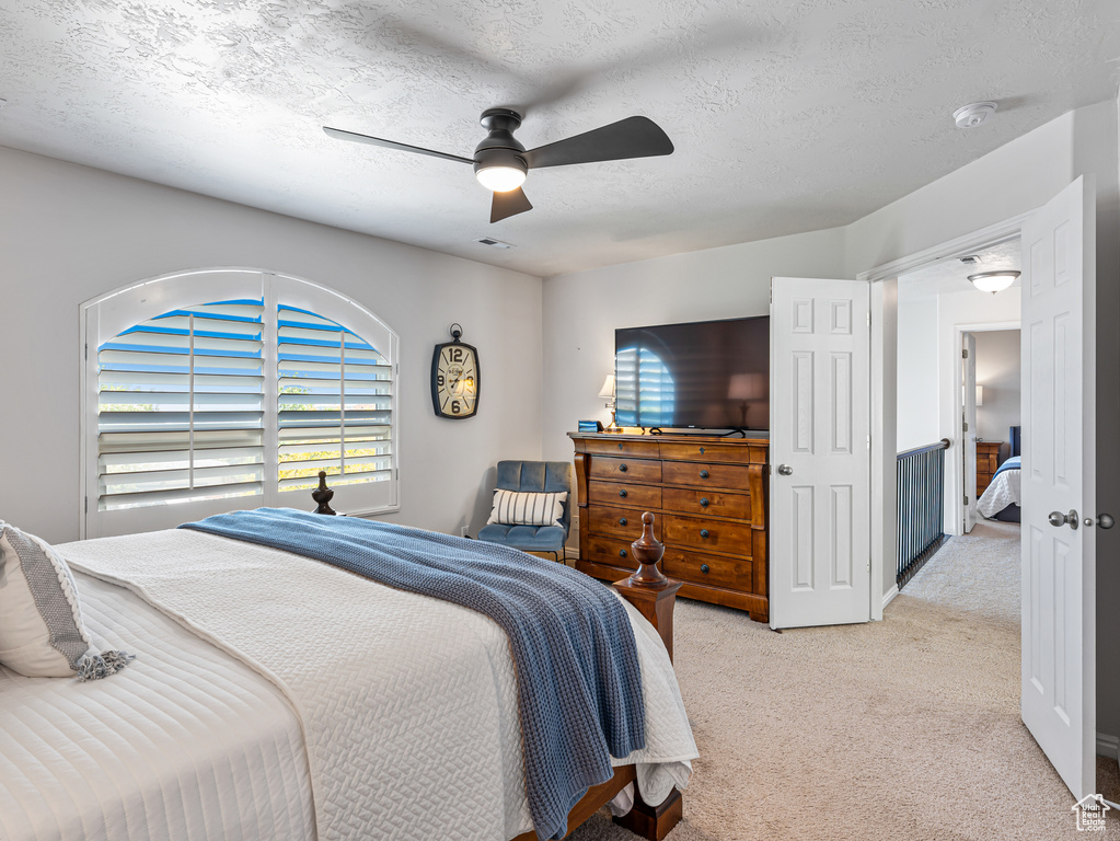 Bedroom featuring light colored carpet, a ceiling fan, and a textured ceiling