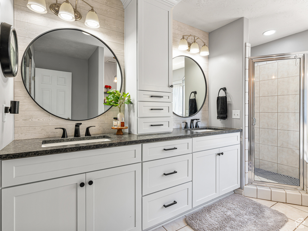 Full bath featuring double vanity, a stall shower, and tile patterned floors