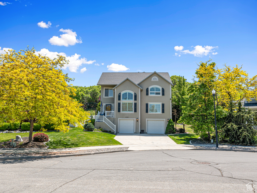 View of front of house featuring driveway, a garage, stairs, stucco siding, and a front lawn