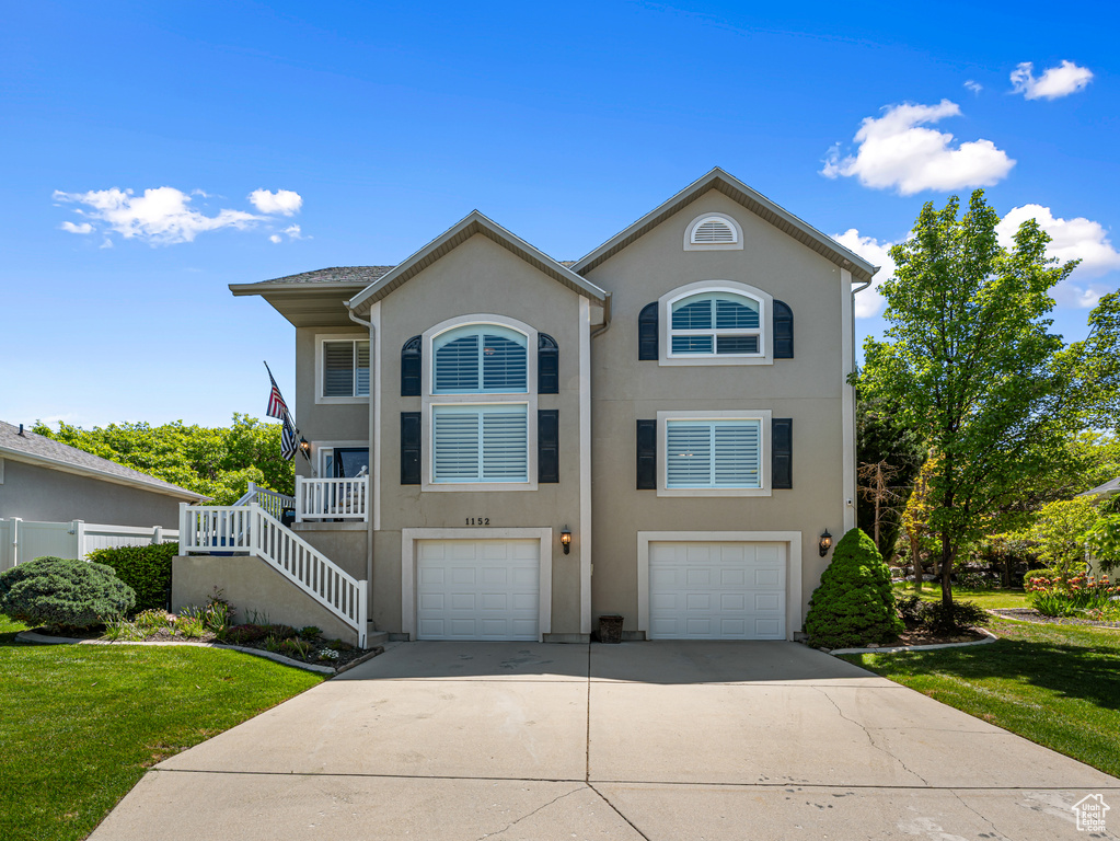View of front facade with a garage, concrete driveway, stucco siding, and stairway