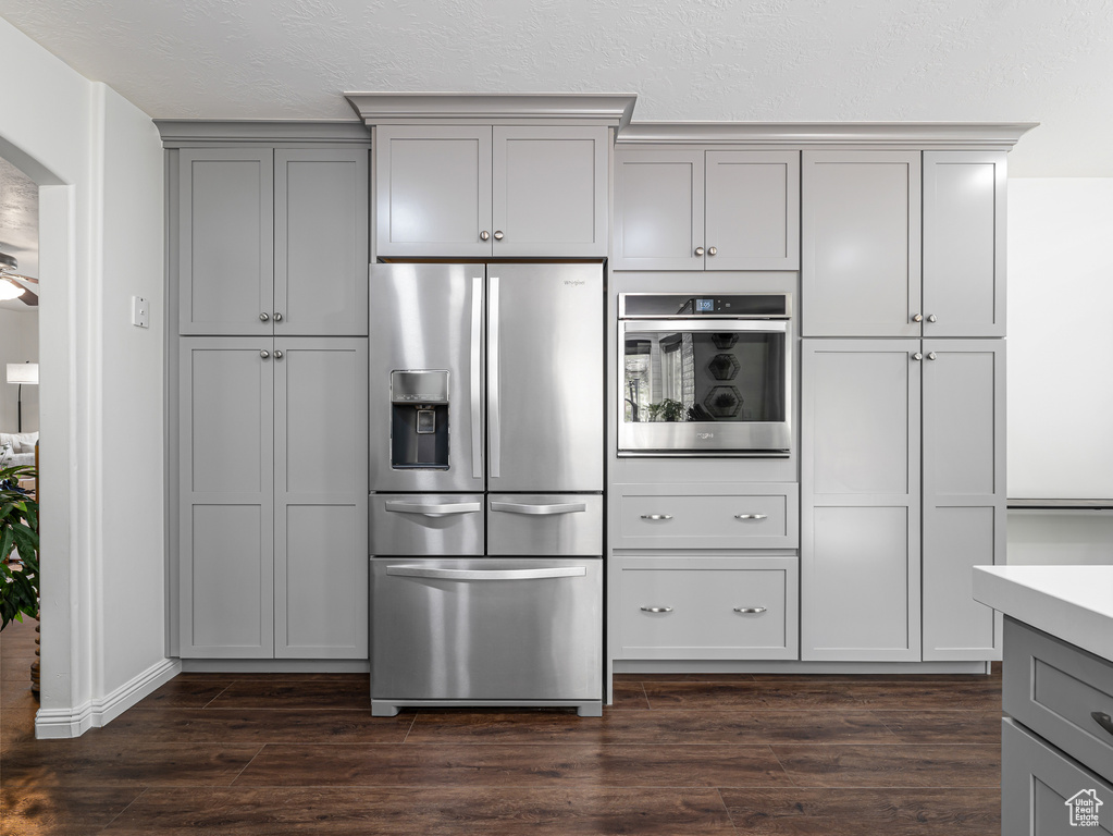 Kitchen featuring stainless steel appliances, gray cabinets, dark wood-style flooring, arched walkways, and light countertops